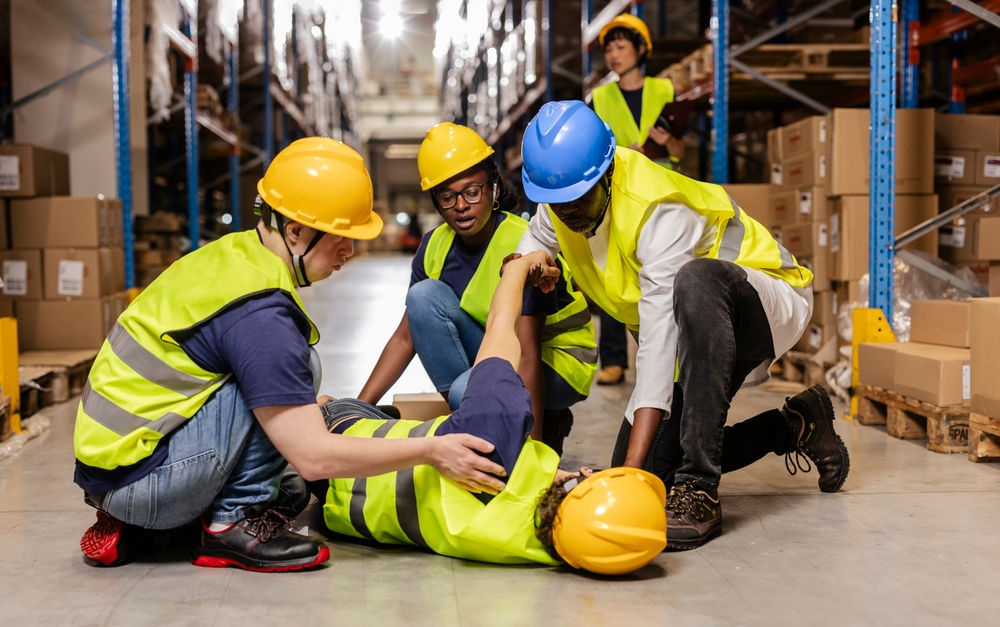 warehouse workers assisting injured colleague lying
